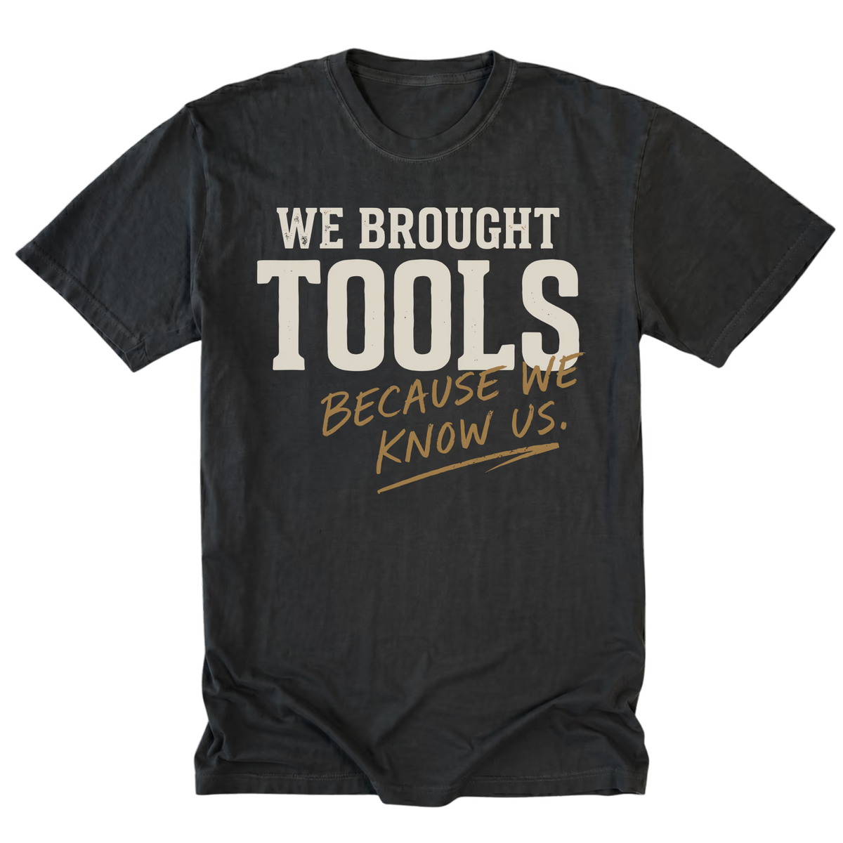 A black t-shirt with a graphic text print reading 'WE BROUGHT TOOLS BECAUSE WE KNOW US.' in cream and gold lettering, displayed flat against a white background.