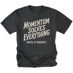 A black short-sleeve t-shirt with a distressed cream-colored graphic text that reads 'MOMENTUM SOLVES EVERYTHING UNTIL IT DOESN'T.' on a solid white background.