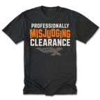 A black t-shirt with a graphic print reading 'PROFESSIONALLY MISJUDGING CLEARANCE' in white and orange lettering, featuring a small gray and orange airplane graphic below, displayed on a clean white background.
