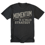 A black t-shirt with a distressed graphic print that reads 'MOMENTUM IS A VALID STRATEGY' in a light beige font, displayed flat against a solid white background.