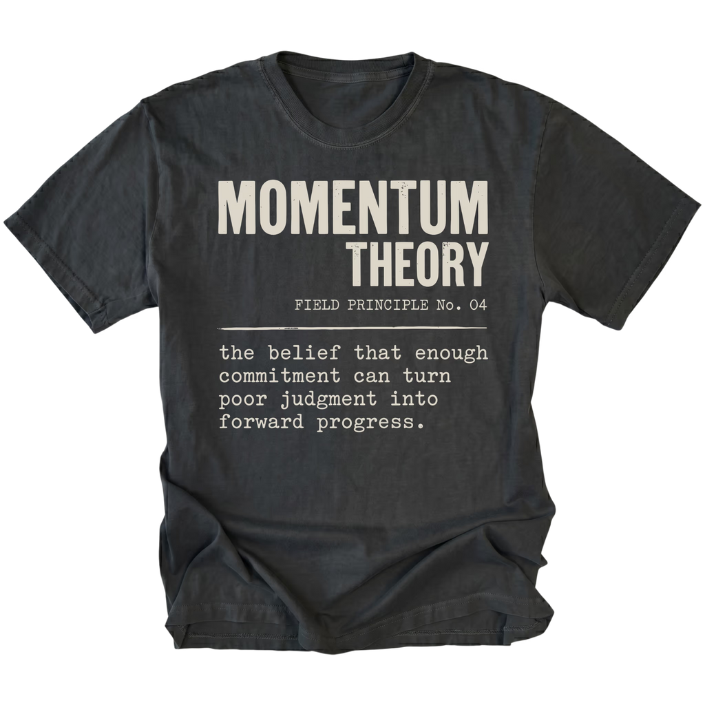 A black t-shirt with a white typewriter-style graphic print that reads 'MOMENTUM THEORY' and a field definition quote underneath, shown on a plain white background.
