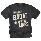 A black graphic t-shirt with the text 'OBVIOUSLY BAD AT FOLLOWING LINES' printed on the front in distressed off-white lettering with olive green accents, shown against a plain white background.
