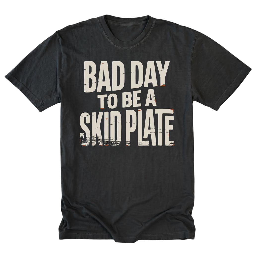 A black tall t-shirt with a distressed white graphic text reading 'BAD DAY TO BE A SKID PLATE' on the front, displayed flat against a solid white background.