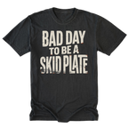 A black tall t-shirt with a distressed white graphic text reading 'BAD DAY TO BE A SKID PLATE' on the front, displayed flat against a solid white background.