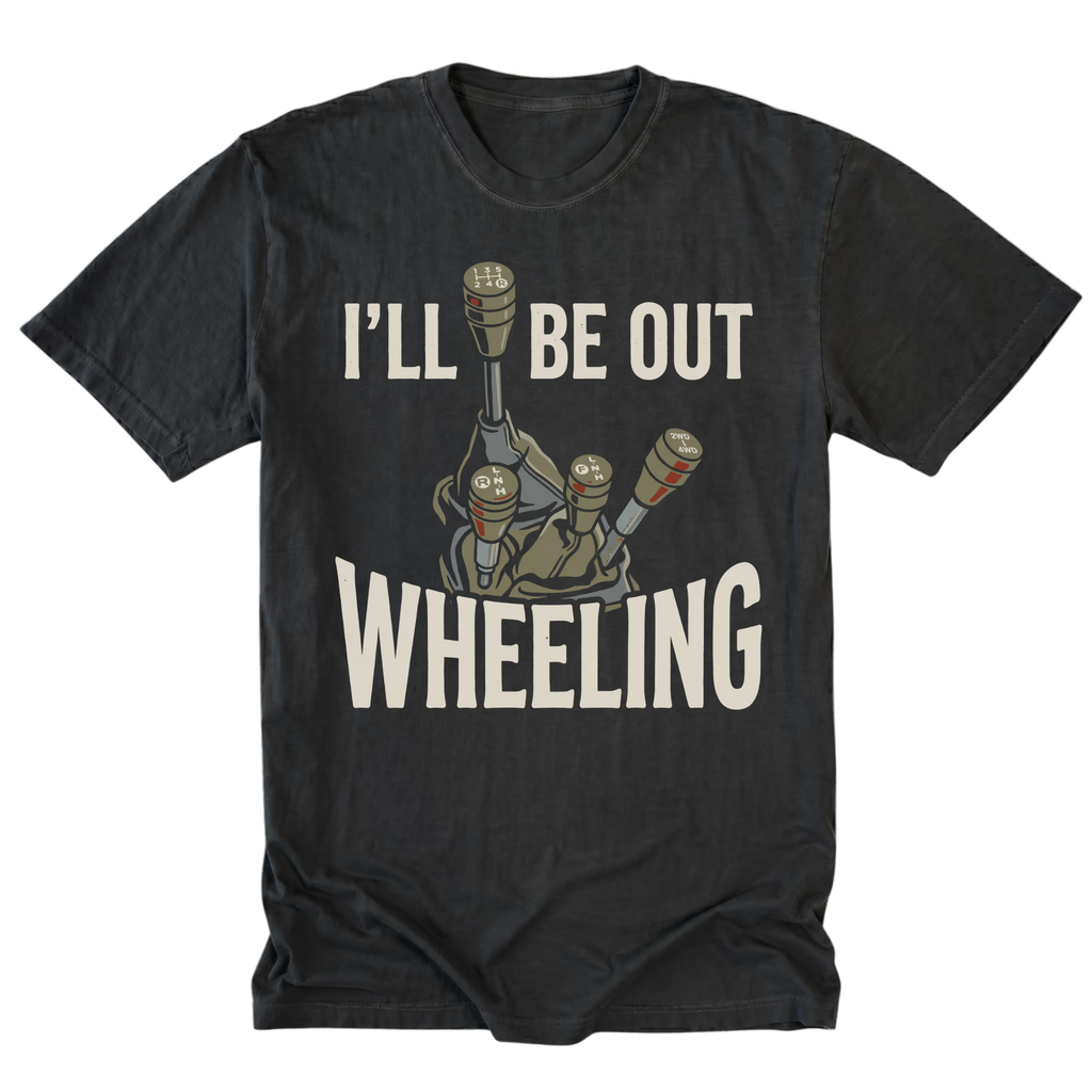 A black t-shirt with a graphic of a manual gear shift console and the text 'I'LL BE OUT WHEELING' in a distressed off-white font, displayed on a solid white background.
