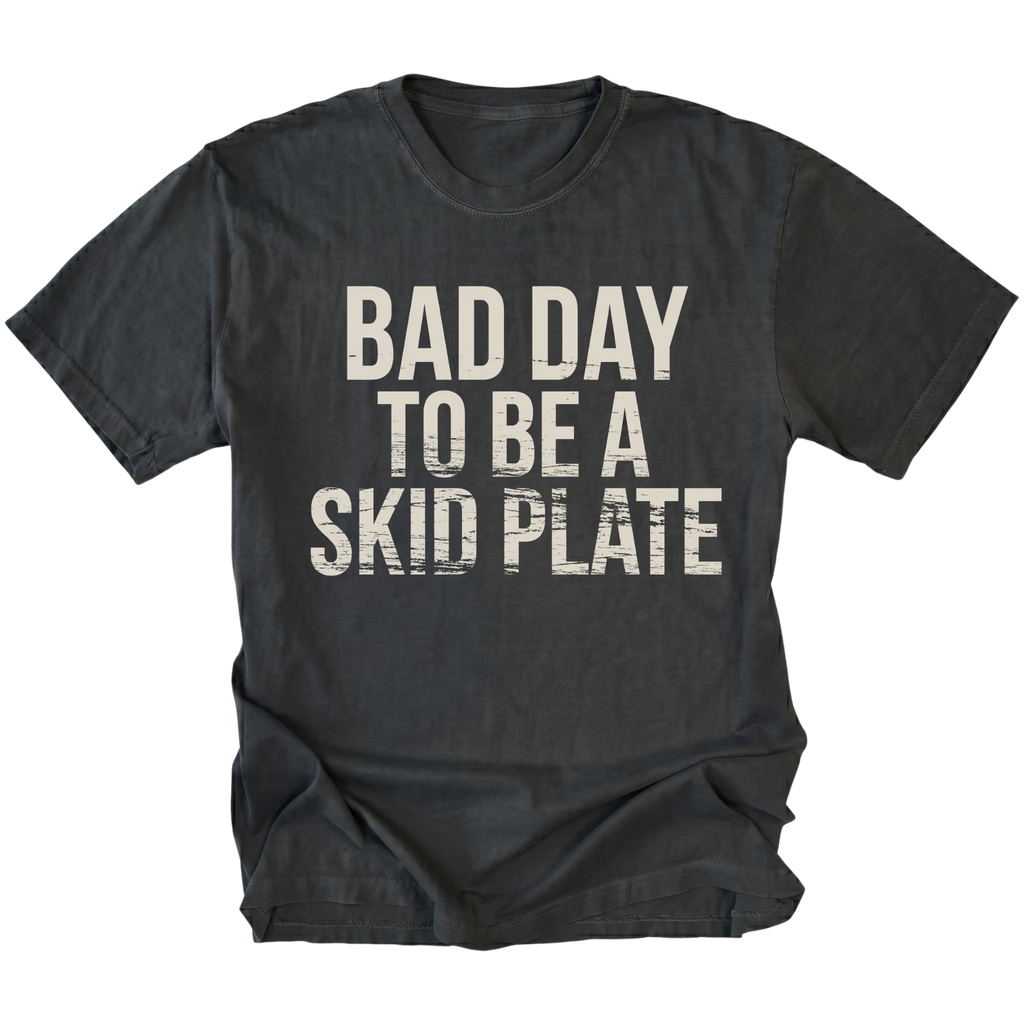 Black t-shirt featuring bold bad day to be a skid plate text graphic shown from the front by Trail Snark.