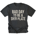 Black t-shirt featuring bold bad day to be a skid plate text graphic shown from the front by Trail Snark.