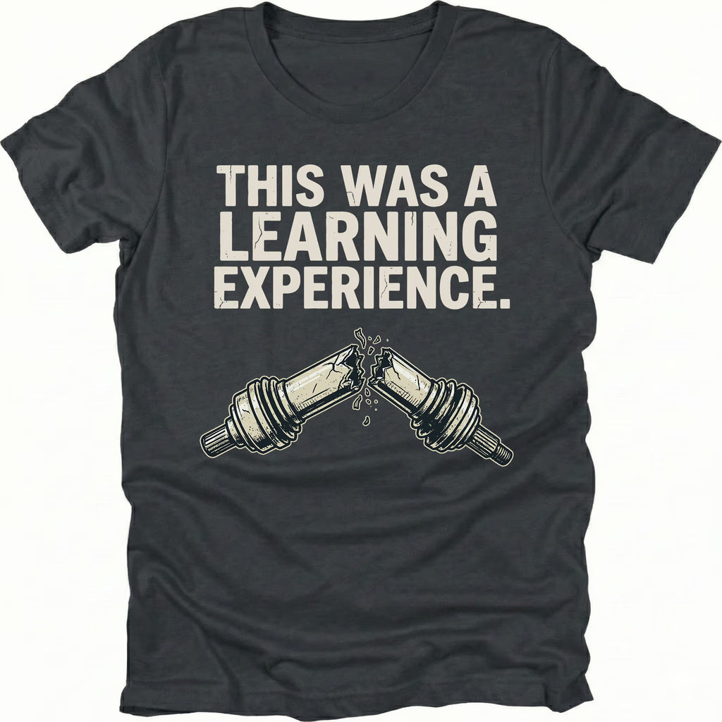 Black t-shirt with text reading “This Was a Learning Experience” above an illustration of a broken axle or CV joint, shown on the front.