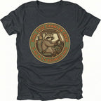 Black t-shirt featuring a raccoon driving a crawler with dual case crawler crew circular badge graphic shown from the front by Trail Snark.