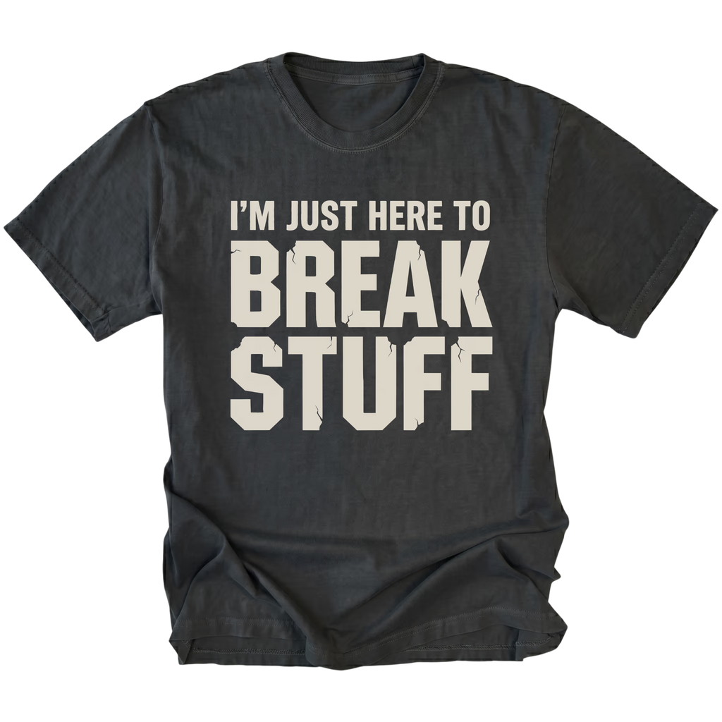 Black t-shirt with bold distressed text reading I’m Just Here To Break Stuff, front view by Trail Snark.
