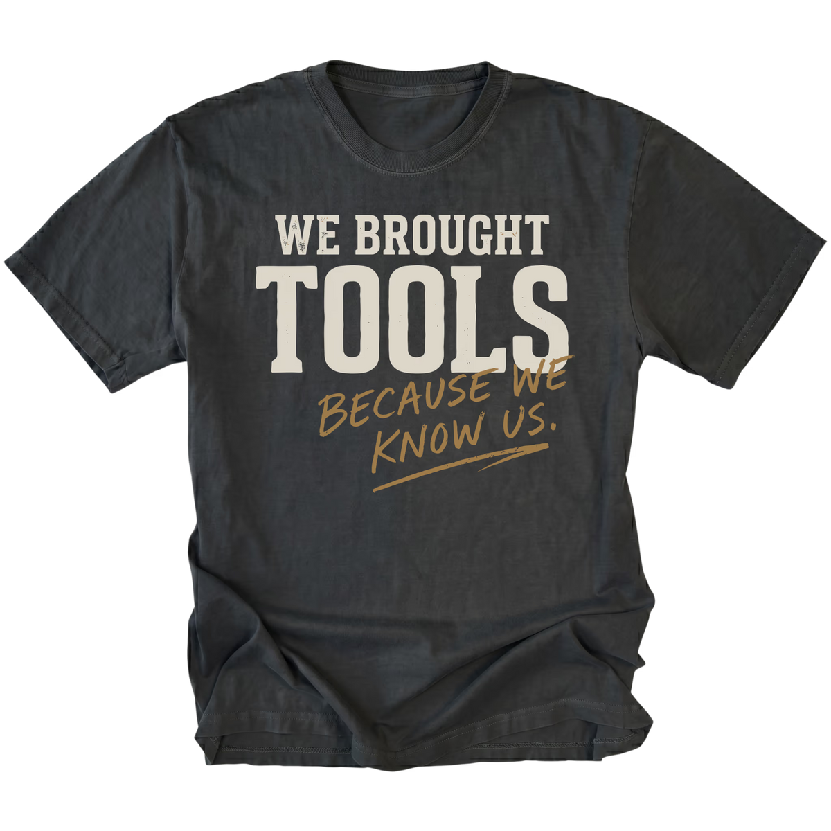 A black t-shirt with a distressed graphic print that reads 'WE BROUGHT TOOLS BECAUSE WE KNOW US.' in cream and tan lettering, displayed on a solid white background.