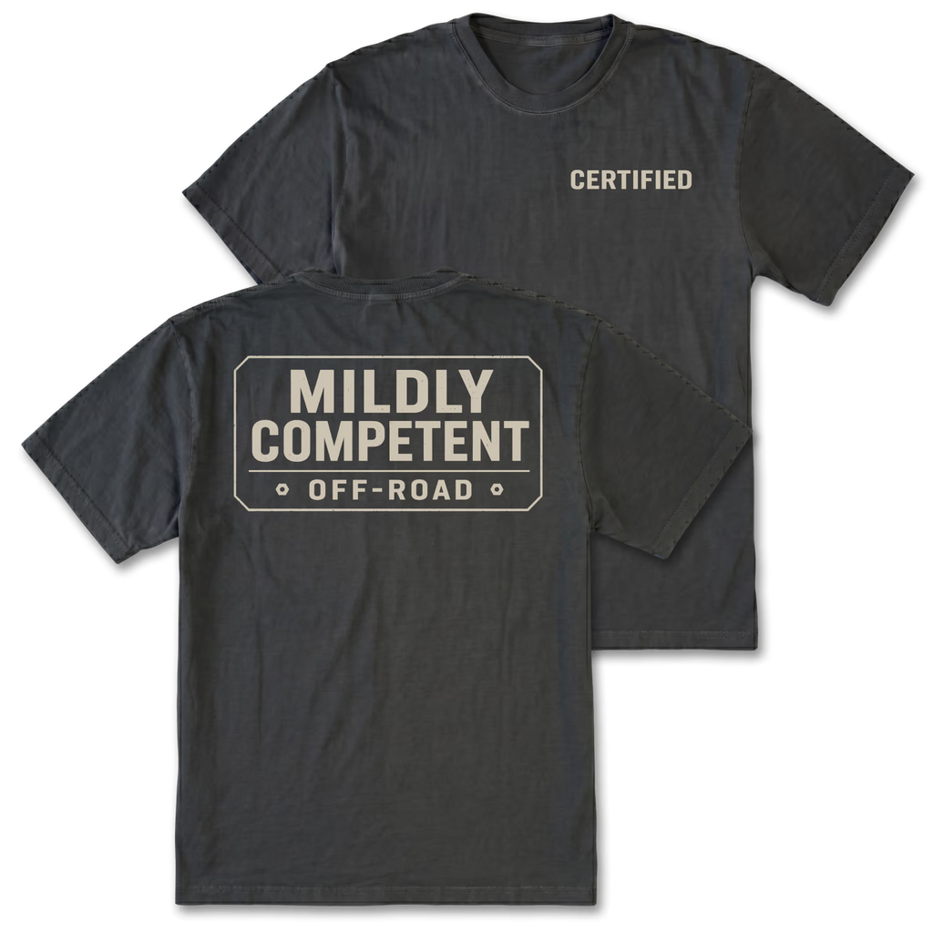 Two dark charcoal gray t-shirts shown on a white background, displaying the front and back designs. The front shirt features the word 'CERTIFIED' printed in beige on the left chest, while the back shirt features a large rectangular graphic with the text 'MILDLY COMPETENT OFF-ROAD' in beige.