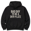 Black pullover hoodie shown from the front, with distressed cream block lettering reading "Bad Day To Be A Skid Plate" across the chest.