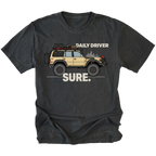 Black t-shirt featuring a built off-road vehicle with daily driver sure text graphic shown from the front by Trail Snark.