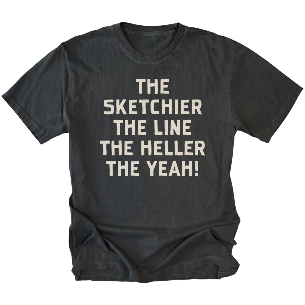 A black t-shirt with cream-colored text on the front that reads 'THE SKETCHIER THE LINE THE HELLER THE YEAH!'. The t-shirt is displayed flat against a solid white background.