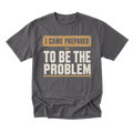 A charcoal gray crewneck t-shirt with a graphic print that reads 'I CAME PREPARED TO BE THE PROBLEM' in beige and off-white lettering, displayed on a clean white background.
