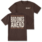 Two dark brown t-shirts shown on a white background, with the front and back views overlapping. The front features a small 'BAD LINE ART' logo on the left chest, and the back features a large graphic print reading 'PROCEED WITH CONFIDENCE BAD LINES AHEAD RESULTS MAY VARY' in cream and orange lettering.