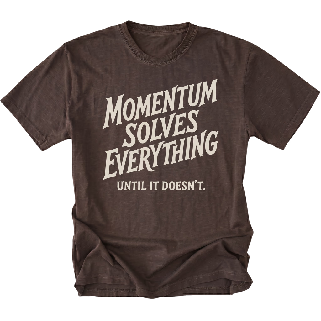 A dark brown short-sleeve t-shirt with a distressed cream-colored graphic text that reads 'MOMENTUM SOLVES EVERYTHING UNTIL IT DOESN'T.' on a solid white background.