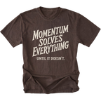 A dark brown short-sleeve t-shirt with a distressed cream-colored graphic text that reads 'MOMENTUM SOLVES EVERYTHING UNTIL IT DOESN'T.' on a solid white background.
