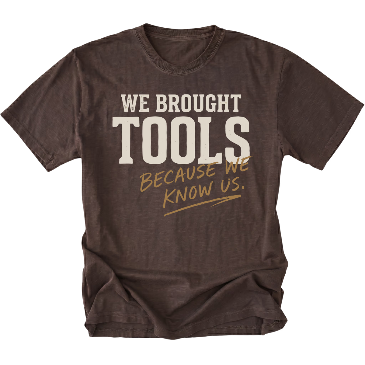 A dark brown heather t-shirt with a distressed graphic that reads 'WE BROUGHT TOOLS BECAUSE WE KNOW US.' in cream and tan lettering, displayed on a solid white background.