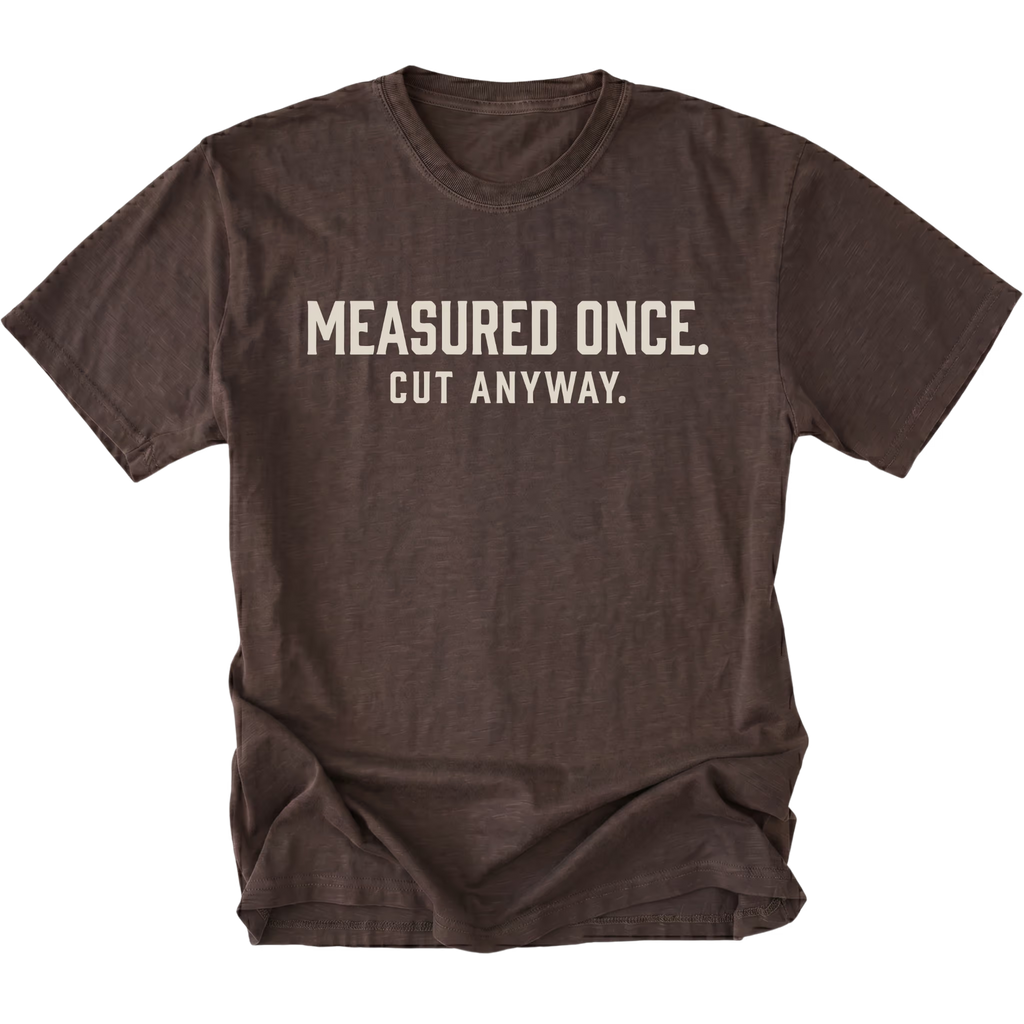 Espresso t-shirt with white text reading Measured Once. Cut Anyway., front view.