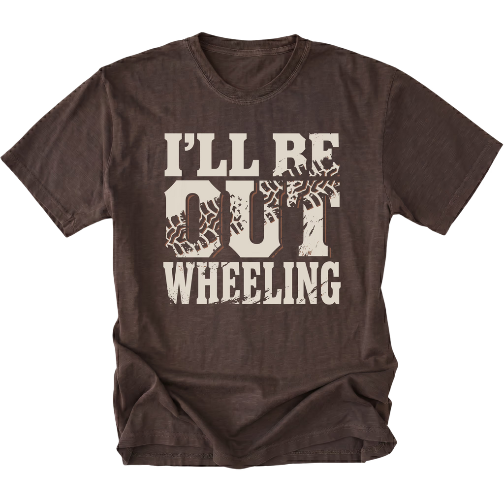 A dark brown short-sleeve t-shirt with a distressed cream graphic on the front that reads 'I'LL BE OUT WHEELING' with tire tracks integrated into the letters, shown on a plain white background.