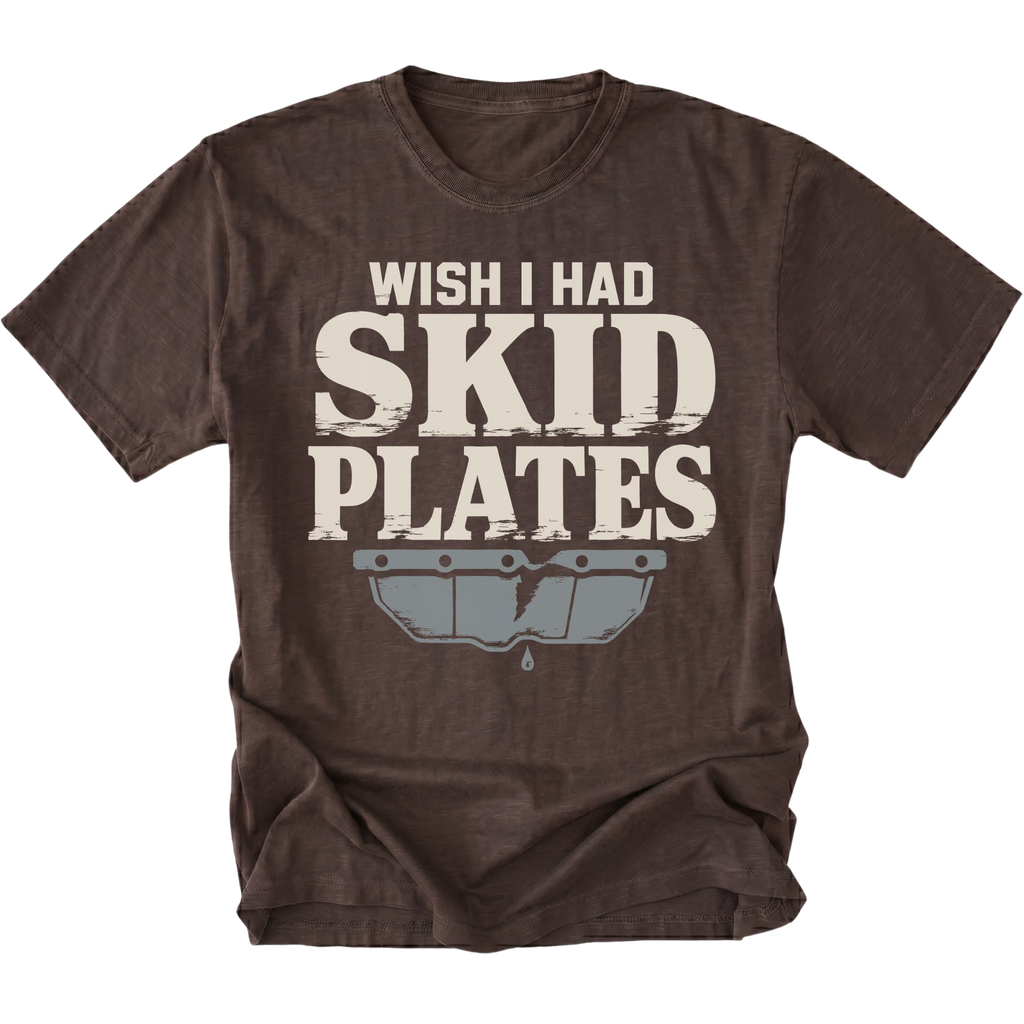 An espresso brown short-sleeve t-shirt with a distressed graphic that reads 'WISH I HAD SKID PLATES' in cream lettering above a gray metallic bumper graphic, shown on a plain white background.
