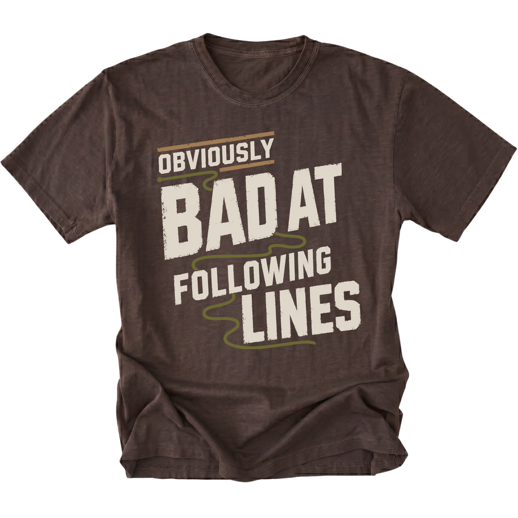 An expresso brown short-sleeve t-shirt with a distressed graphic that reads 'OBVIOUSLY BAD AT FOLLOWING LINES' in cream and olive green text, displayed on a clean white background.