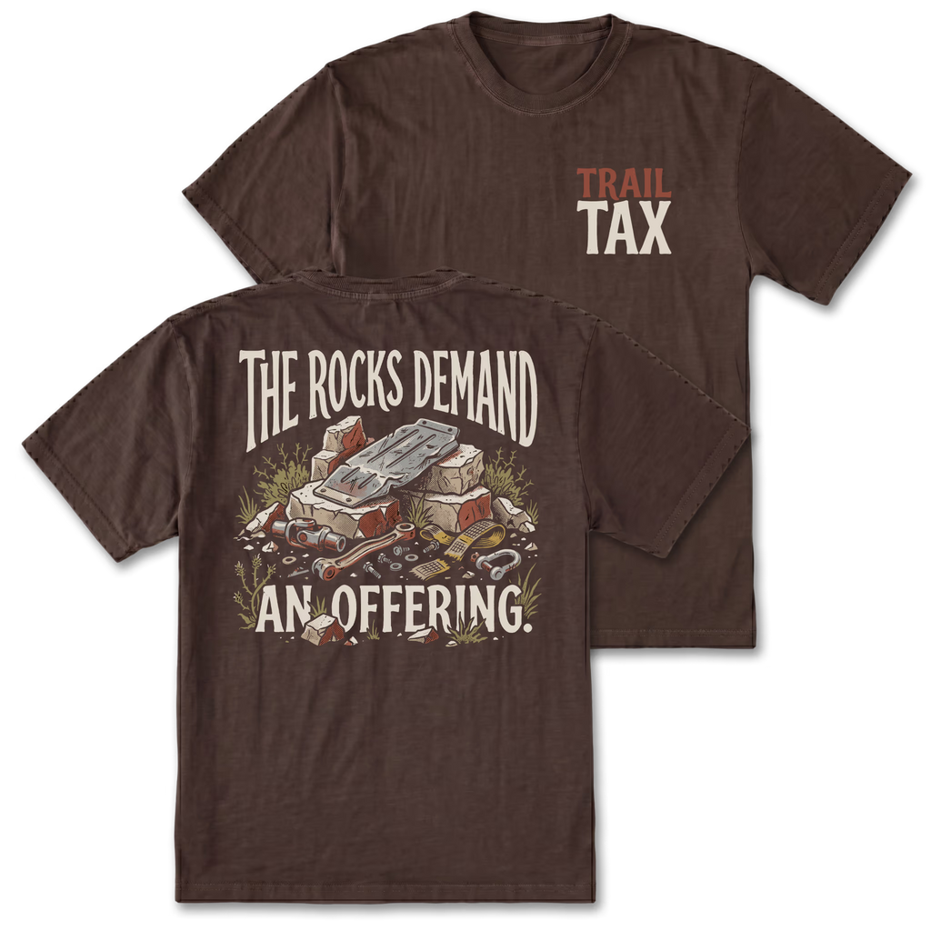 Two brown short-sleeve graphic T-shirts shown on a white background, with the front view behind and the back view in front. The front chest has small 'TRAIL TAX' text in orange and off-white.