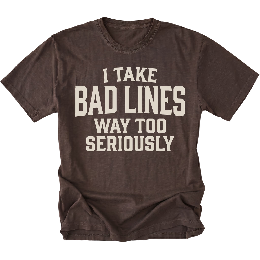 A dark brown short-sleeve t-shirt with a distressed cream-colored text graphic that reads 'I TAKE BAD LINES WAY TOO SERIOUSLY' on the front, displayed against a solid white background.