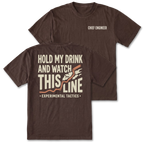 Two dark brown t-shirts shown on a white background, displaying both the front and back designs. The front shirt features the text 'CHIEF ENGINEER' in white on the left chest. The back features the text 'HOLD MY DRINK AND WATCH THIS LINE' and smaller text 'EXPERIMENTAL TACTICS' under.