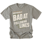 A gray short-sleeve t-shirt with a graphic print that reads 'OBVIOUSLY BAD AT FOLLOWING LINES' in distressed off-white lettering with olive green and tan accent lines, shown on a plain white background.