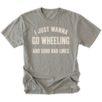 A gray t-shirt with distressed cream-colored text that reads 'I JUST WANNA GO WHEELING AND SEND BAD LINES' on a solid white background.