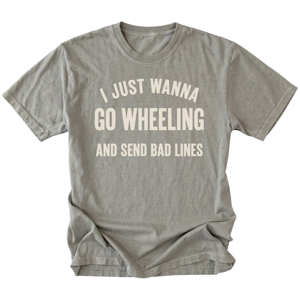 A gray t-shirt with distressed cream-colored text that reads 'I JUST WANNA GO WHEELING AND SEND BAD LINES' on a solid white background.