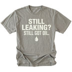 Grey T-Shirt featuring the Still Leaking? Still Got Oil. design with an oil drop graphic on the front view by Trail Snark.