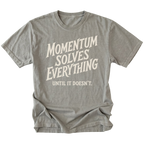A gray short-sleeve t-shirt with a distressed cream-colored graphic text that reads 'MOMENTUM SOLVES EVERYTHING UNTIL IT DOESN'T.' on a solid white background.