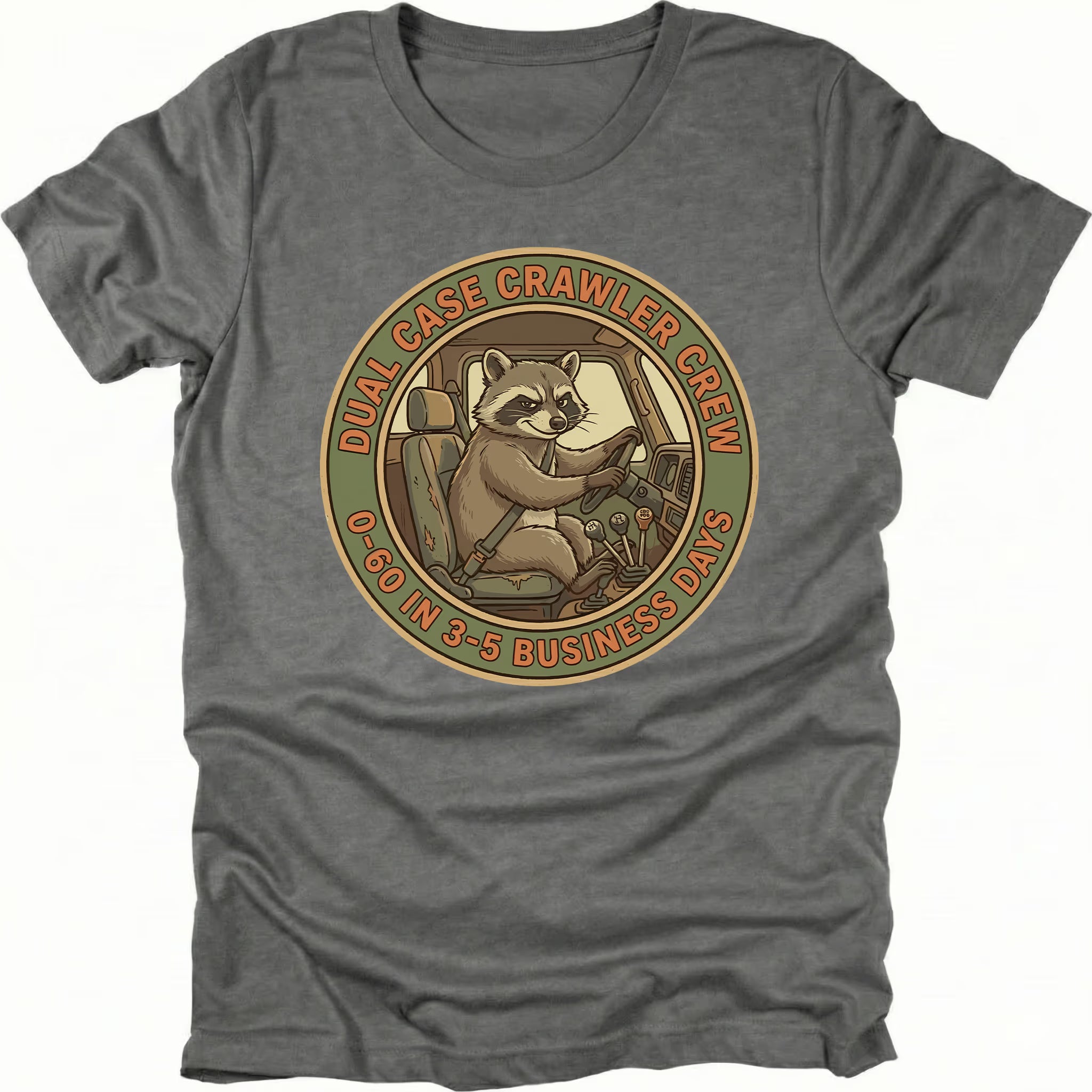 Grey t-shirt featuring a raccoon driving a crawler with dual case crawler crew circular badge graphic shown from the front by Trail Snark.