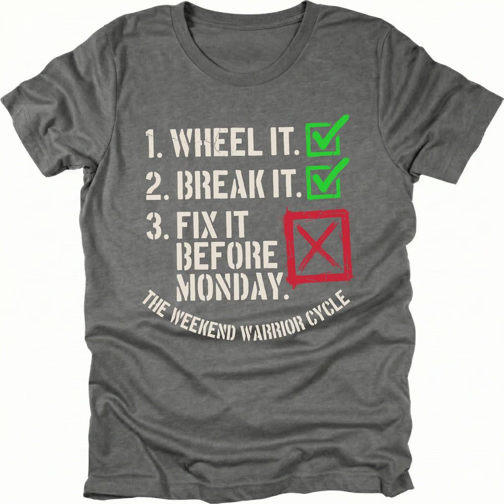 Grey t-shirt with checklist text reading “1. Wheel It. 2. Break It. 3. Fix It Before Monday” with checkmarks and a red X, labeled “The Weekend Warrior Cycle.”