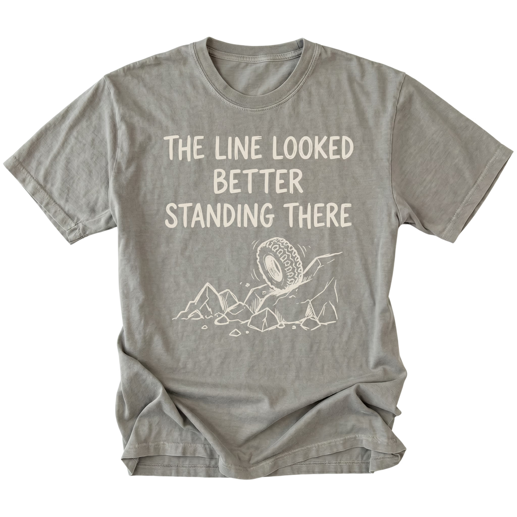 Grey T-Shirt with hand-drawn tire and rocks graphic and text reading “The Line Looked Better Standing There” shown on front view by Trail Snark.