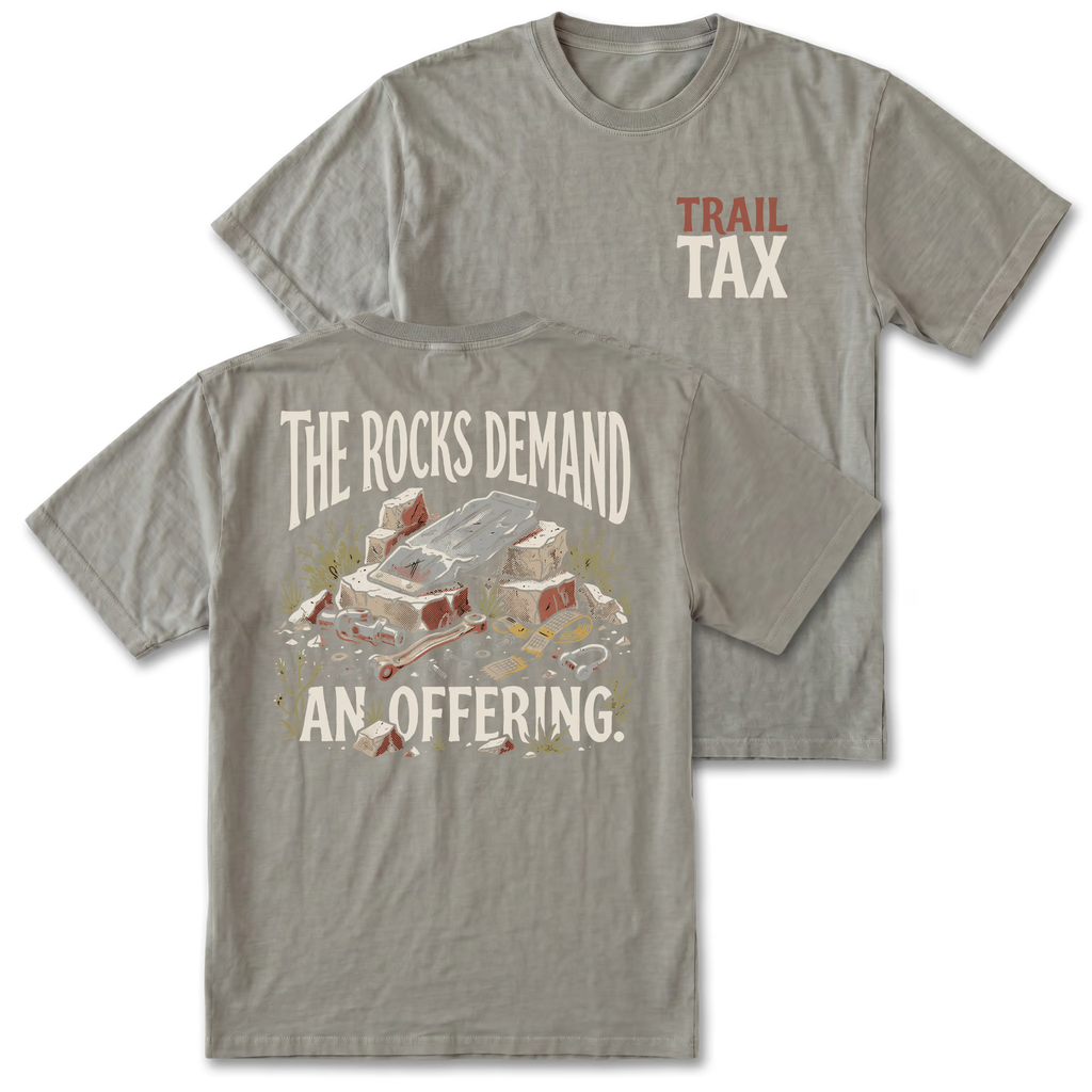 A gray t-shirt shown from both the front and back. The front features a small chest graphic reading 'TRAIL TAX' in red and cream.
