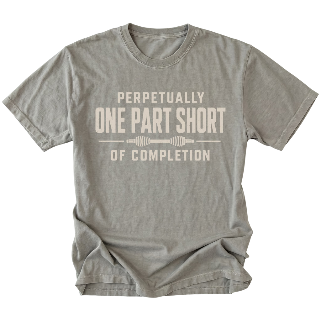 Grey T-shirt with a Perpetually One Part Short Of Completion garage build design shown from the front by Trail Snark.