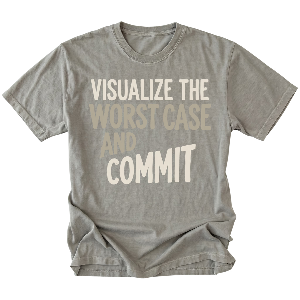A gray short-sleeve t-shirt with a graphic text print reading 'VISUALIZE THE WORST CASE AND COMMIT' in cream and light beige lettering, displayed flat against a solid white background.