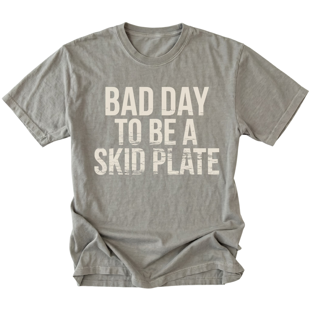 Grey t-shirt featuring bold bad day to be a skid plate text graphic shown from the front by Trail Snark.