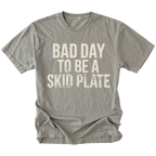 Grey t-shirt featuring bold bad day to be a skid plate text graphic shown from the front by Trail Snark.