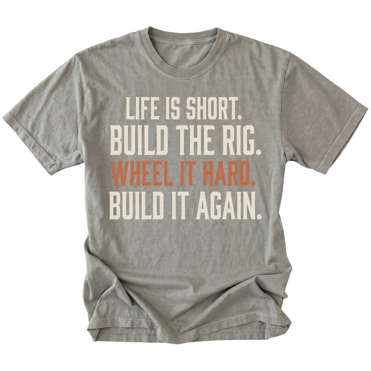 A gray short-sleeve t-shirt with a distressed white and orange text graphic on the front reading 'LIFE IS SHORT. BUILD THE RIG. WHEEL IT HARD. BUILD IT AGAIN.'