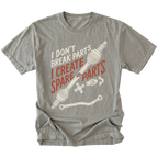 A heather gray short-sleeve t-shirt with a graphic print of a car axle and parts, featuring the text 'I DON'T BREAK PARTS I CREATE SPARE PARTS' in white and orange-red lettering, shown on a plain white background.