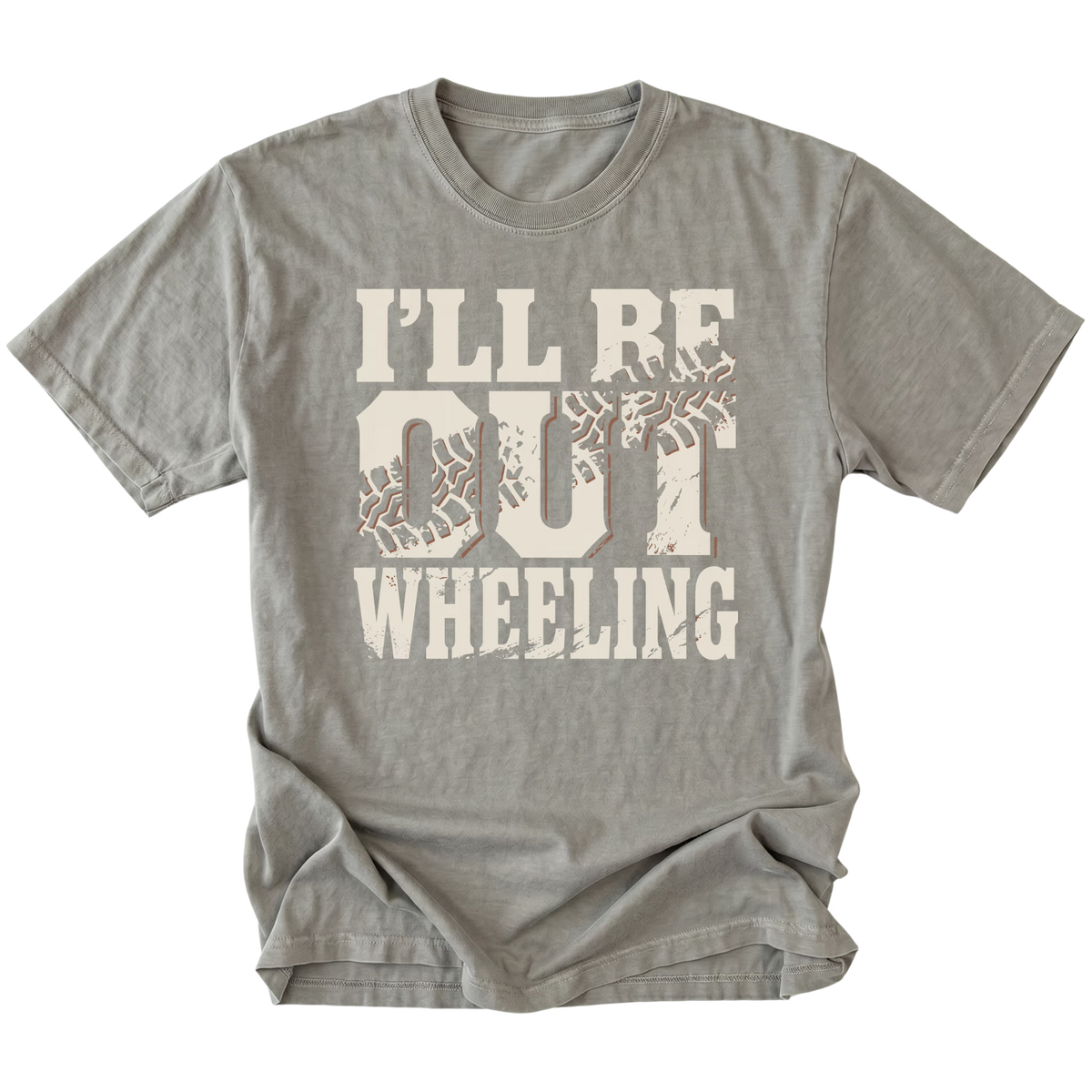 A gray crewneck t-shirt with a distressed graphic on the front that reads 'I'LL BE OUT WHEELING' in cream lettering, featuring tire tracks inside the letters 'OUT'.
