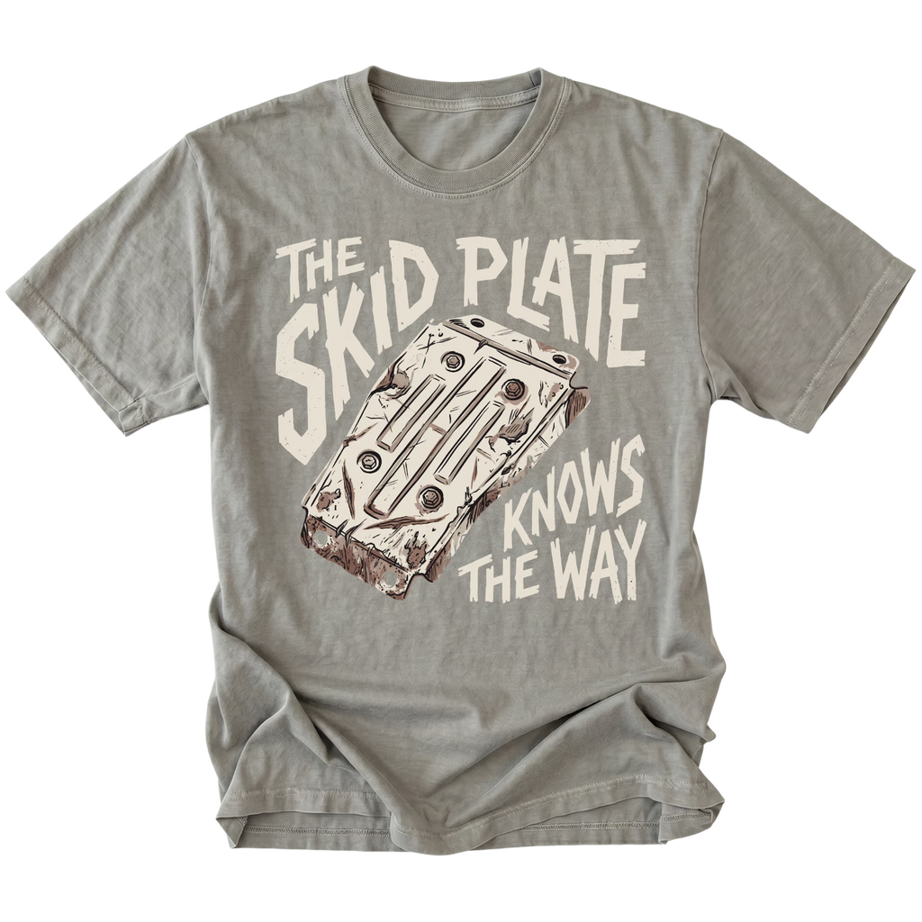 A gray crewneck t-shirt featuring a vintage-style graphic of a cassette deck with the text 'THE SKID PLATE KNOWS THE WAY' in cream and brown.