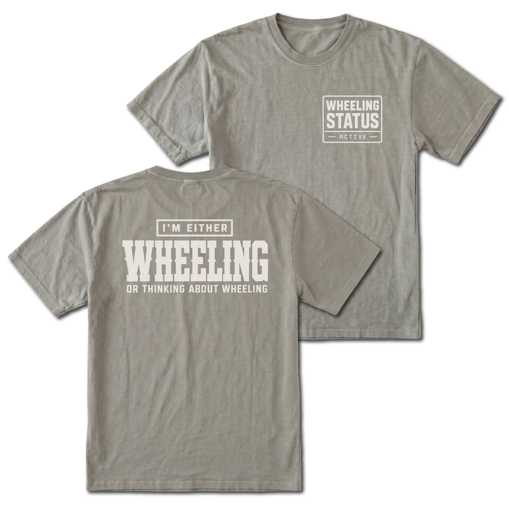 Grey T-shirt with I'm Either Wheeling Or Thinking About Wheeling back design and Wheeling Status front chest print by Trail Snark.