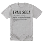 A light steel gray short-sleeve t-shirt with a black printed graphic on the front. The graphic features the text 'TRAIL SODA' in a bold serif font, followed by a dictionary-style definition: 'n.